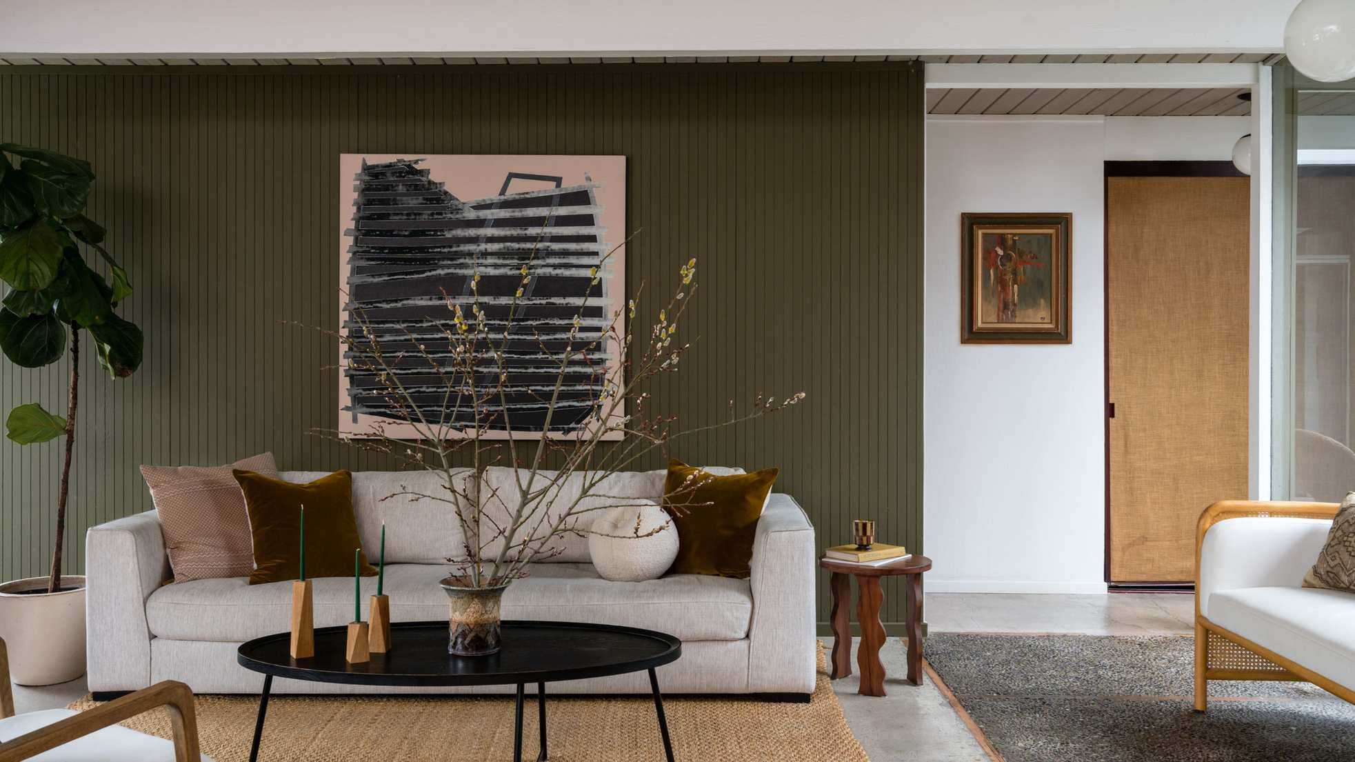 Open plan living room with a green feature wall and a beige sofa
