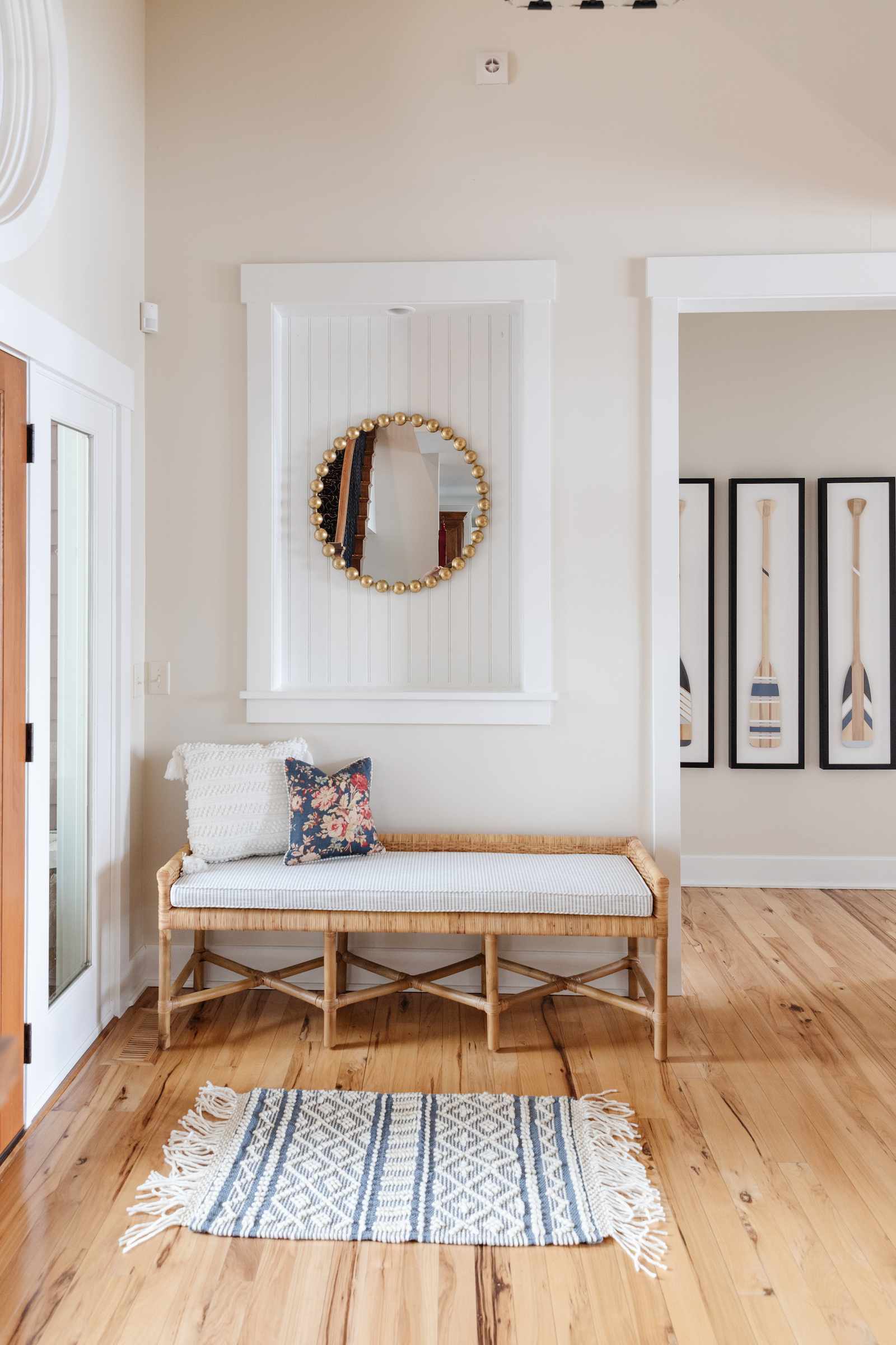 hallway with wooden floor and blue and white stripe rug gold mirror and oar artwork