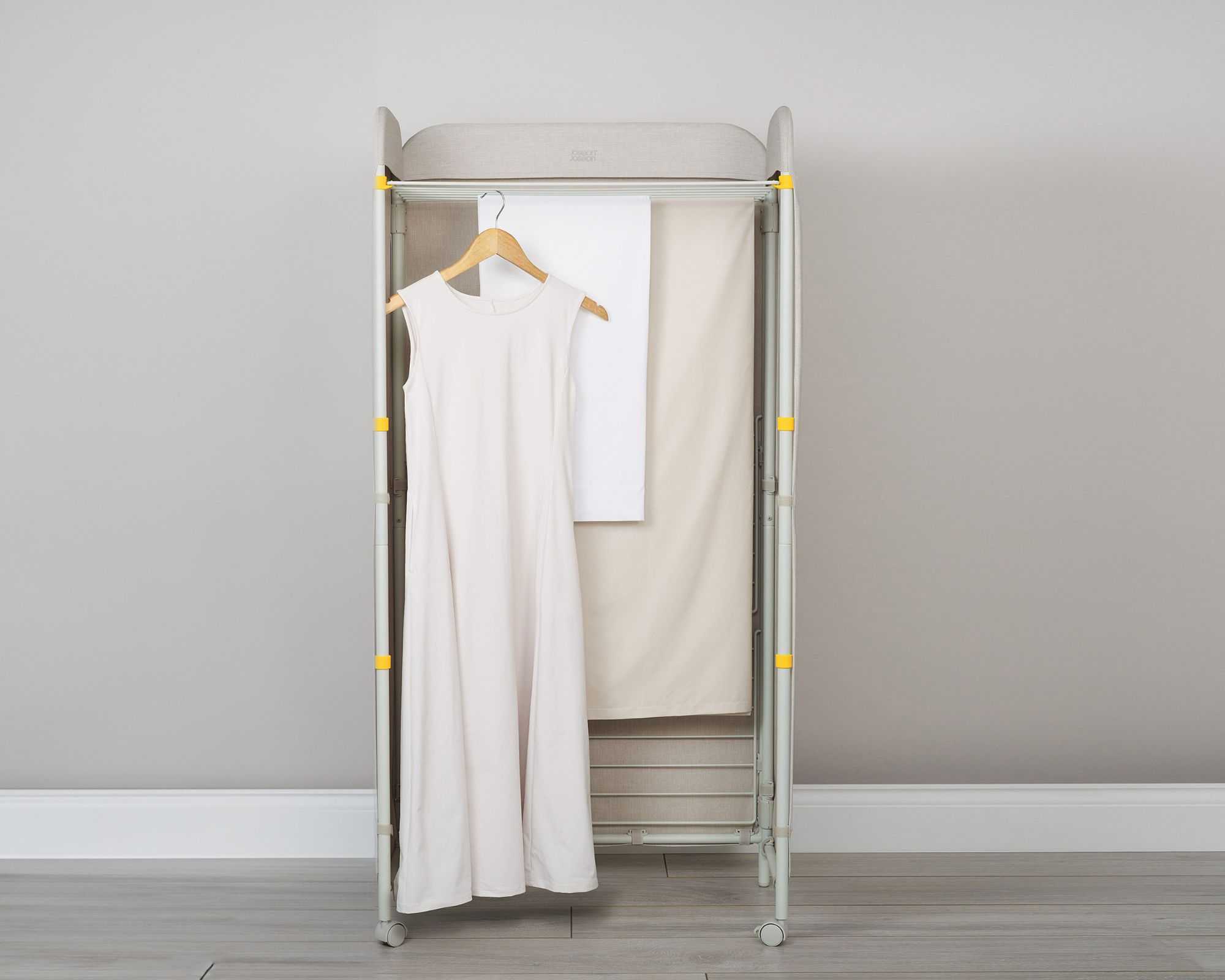 The Eclipse&trade; 3-tier Ecru Screen Airer with a dress hanging on a hanger