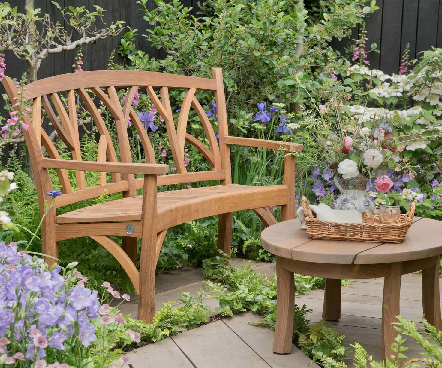 wooden bench on a deck with pockets of ground cover plants in the deck