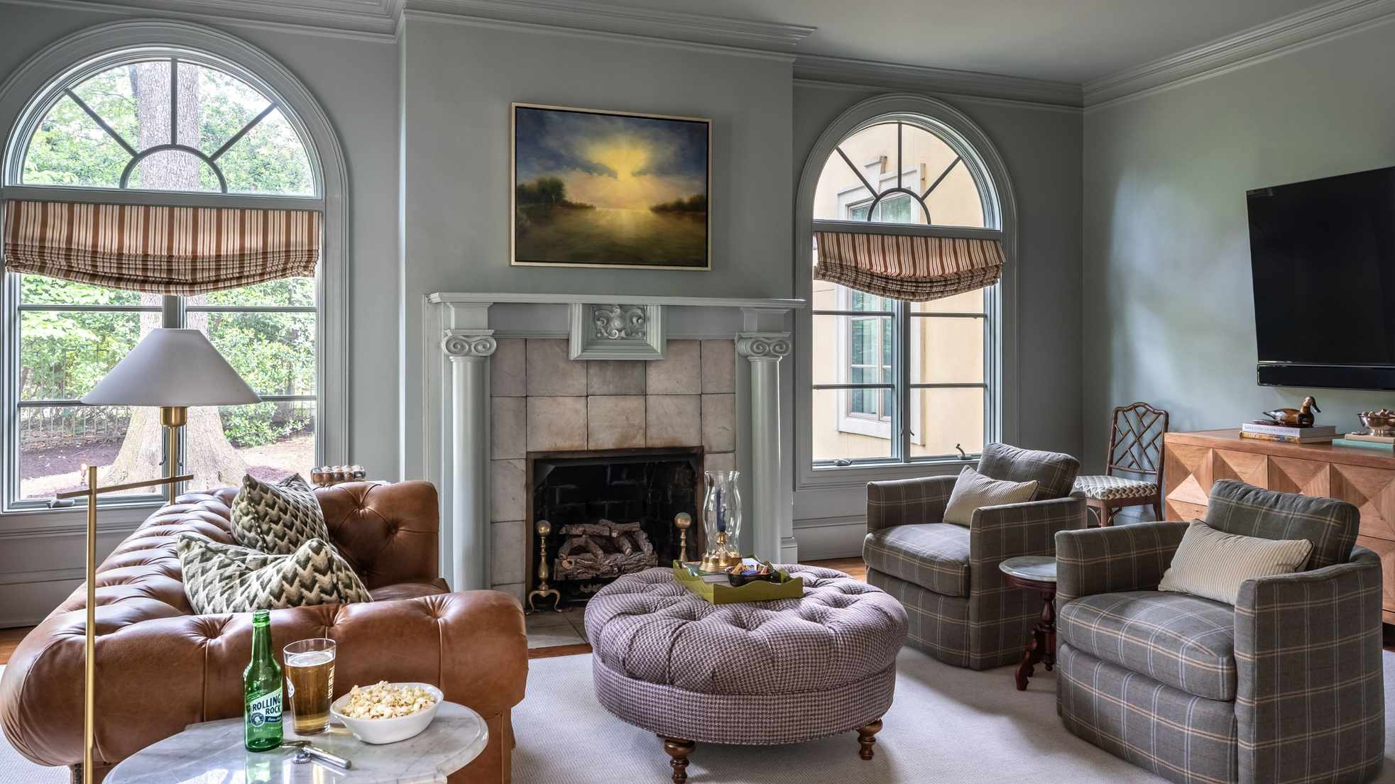 Blue living room with a tqna leather sofa, check armchairs and a wooden sideboard