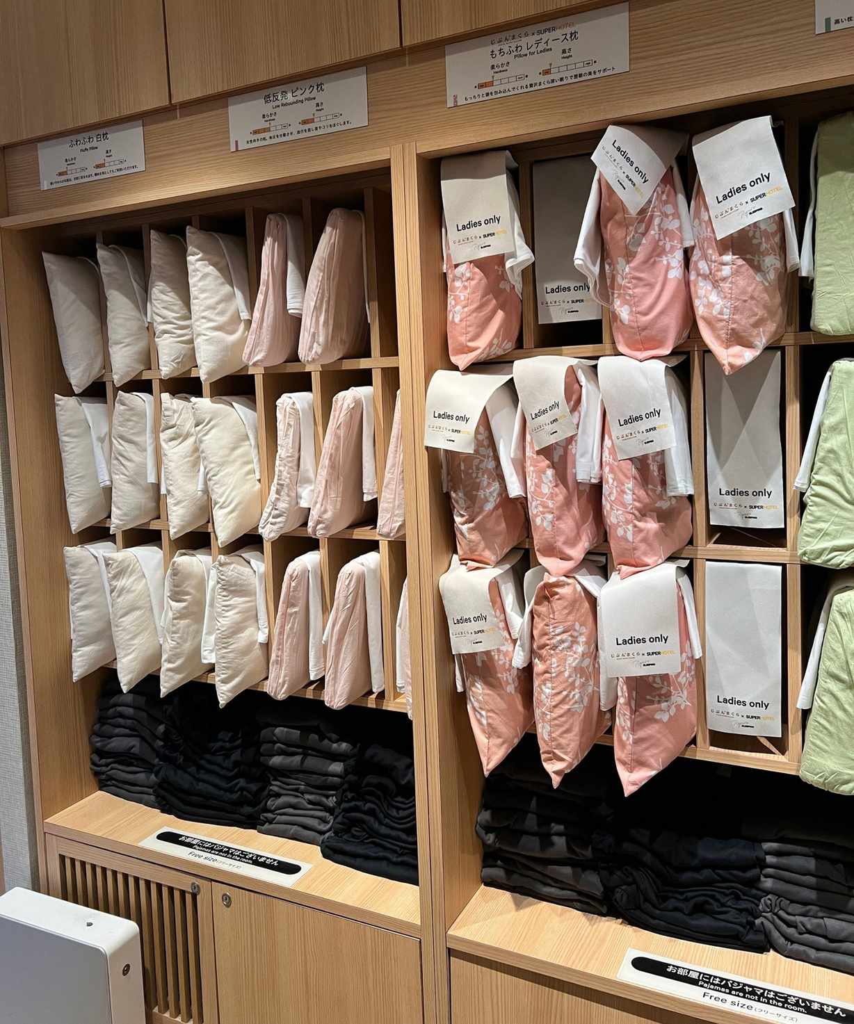 A wooden shelving unit filled with different pillows in different colored pillowcases.