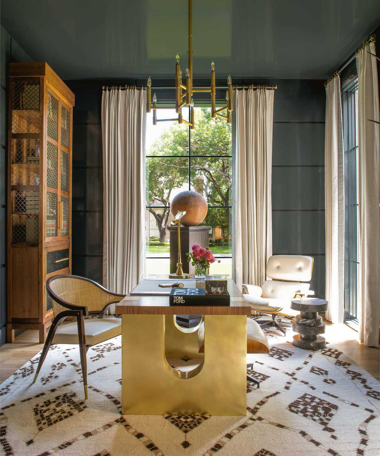 A moody office with a brown and white patterned rug and a chandelier light fixture