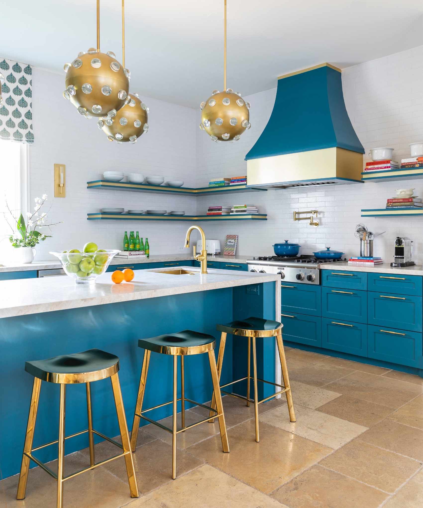 kitchen renovation rules, teal blue and white kitchen with metallic brass fixtures and fittings, open plan shelving, stone tiled floor, large cooker hood