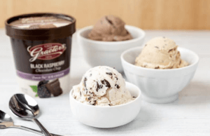 Three bowls of ice cream are pictured. At left, there are two spoons. In the background is a pint of ice cream.