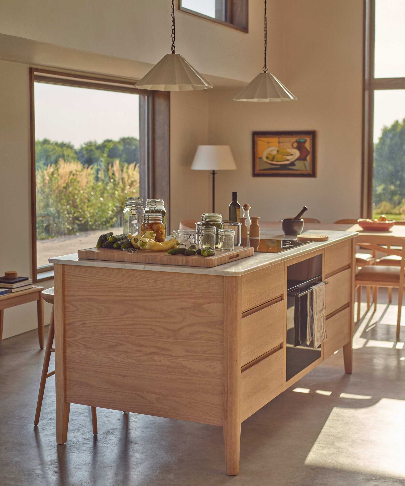 A neutral kitchen with a wooden island housing an oven and lots of drawer storage