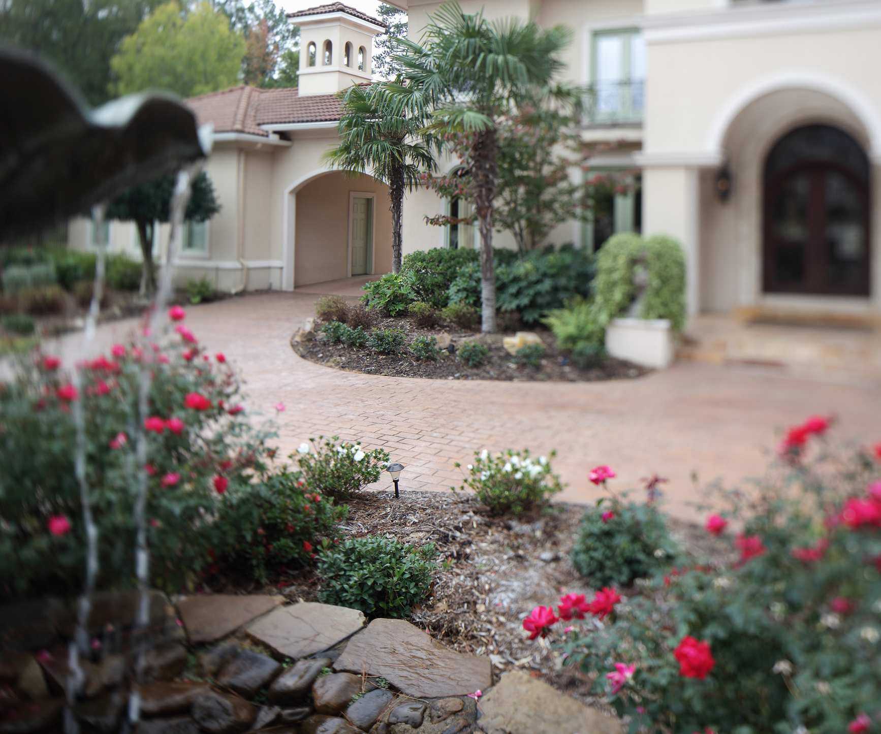 A front driveway with two large planting beds filled with flowers