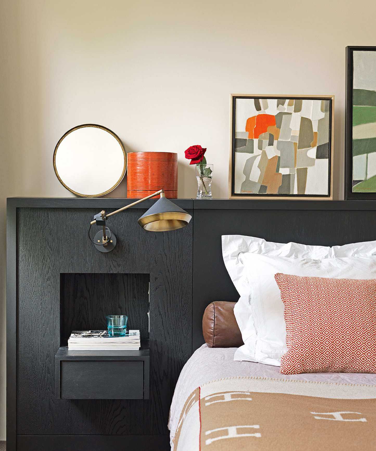 Built in headboard and storage in black with bed dressed in white and pink.