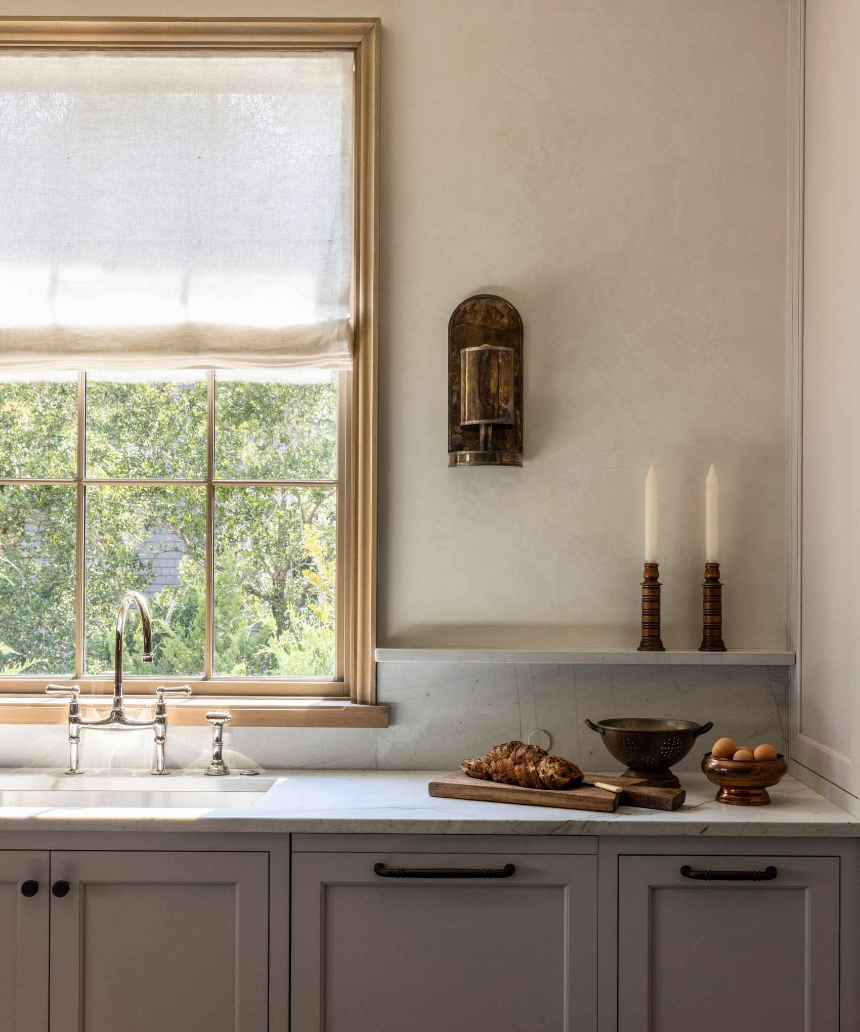 A small kitchen with deep taupe cabinets, marble countertops, and a arm white textured wall paint
