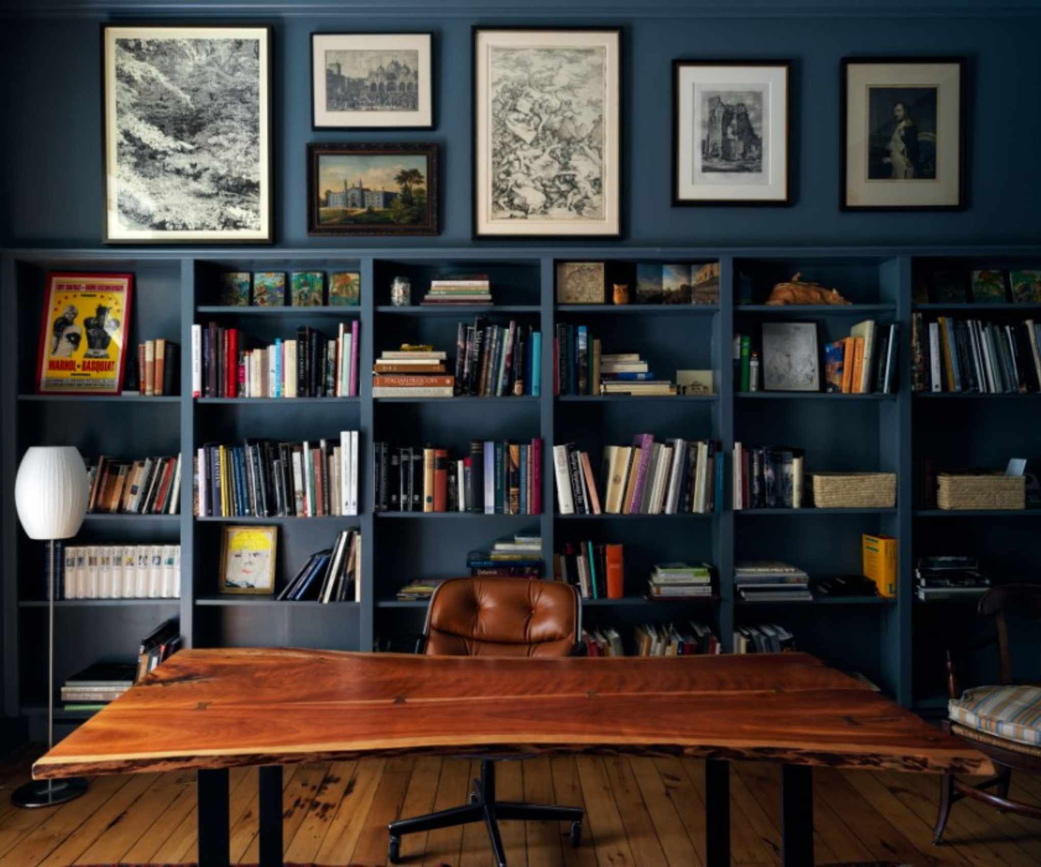 Navy home office with bookshelves and wooden desk and brown leather chair