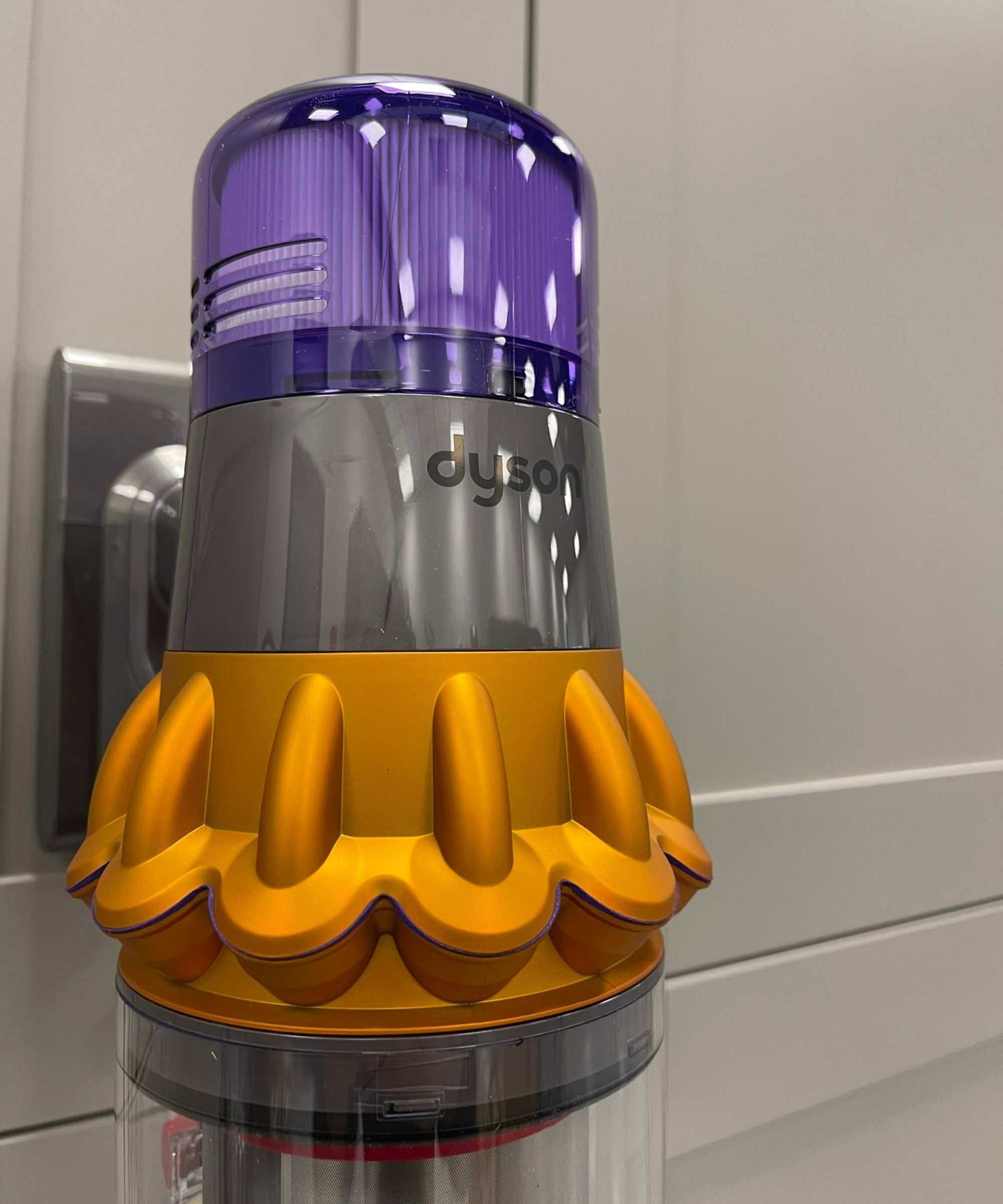 Close up of the main purple, orange and gray vacuum unit of the Dyson V15 Detect. It looks futuristic and unlike any other vacuum