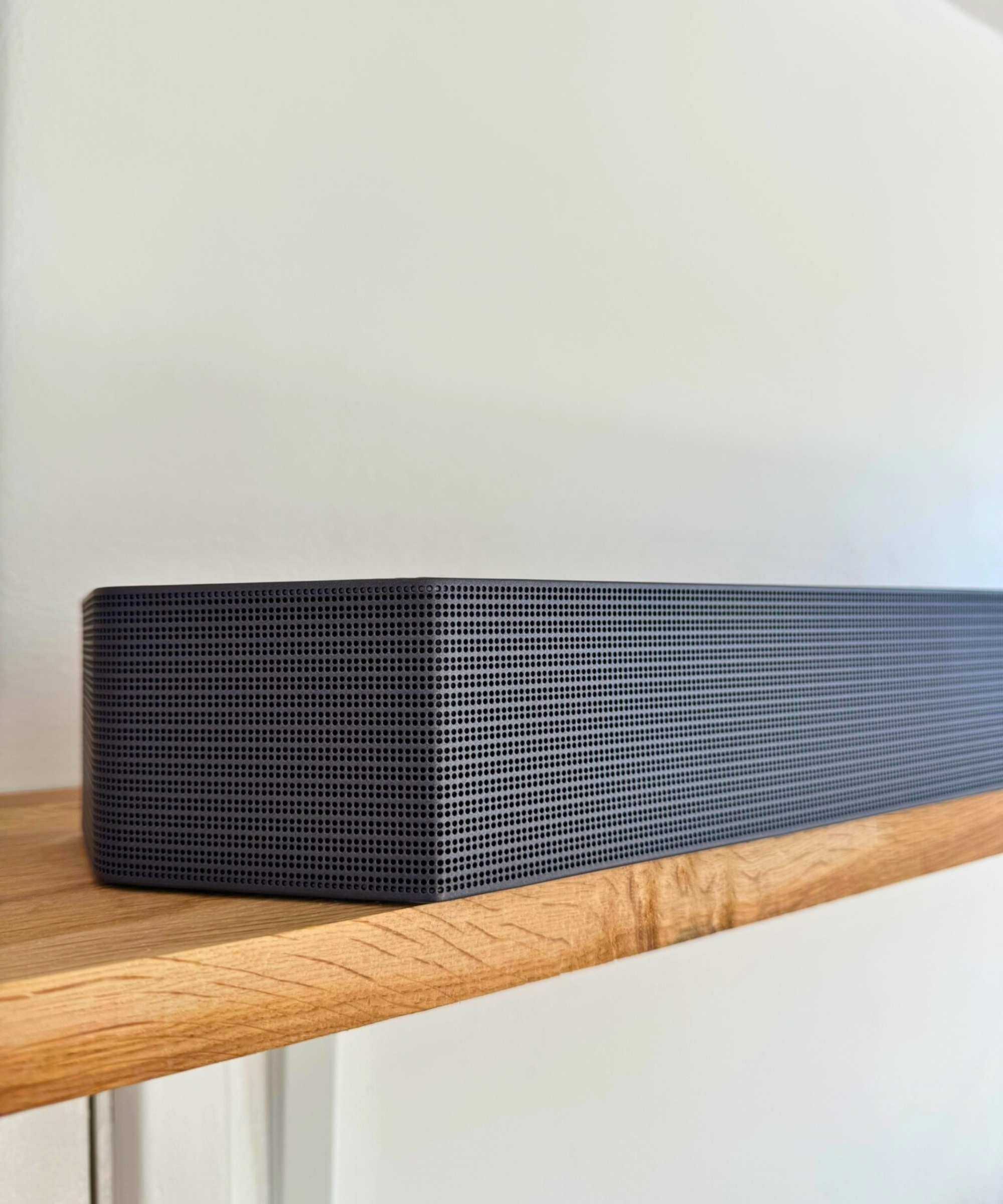 Samsung HW-Q990F soundbar on wooden shelf.