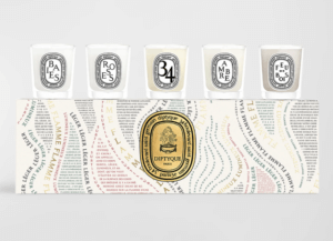 This is an image of a patterned box with a gold logo in the center. On top are five candles.