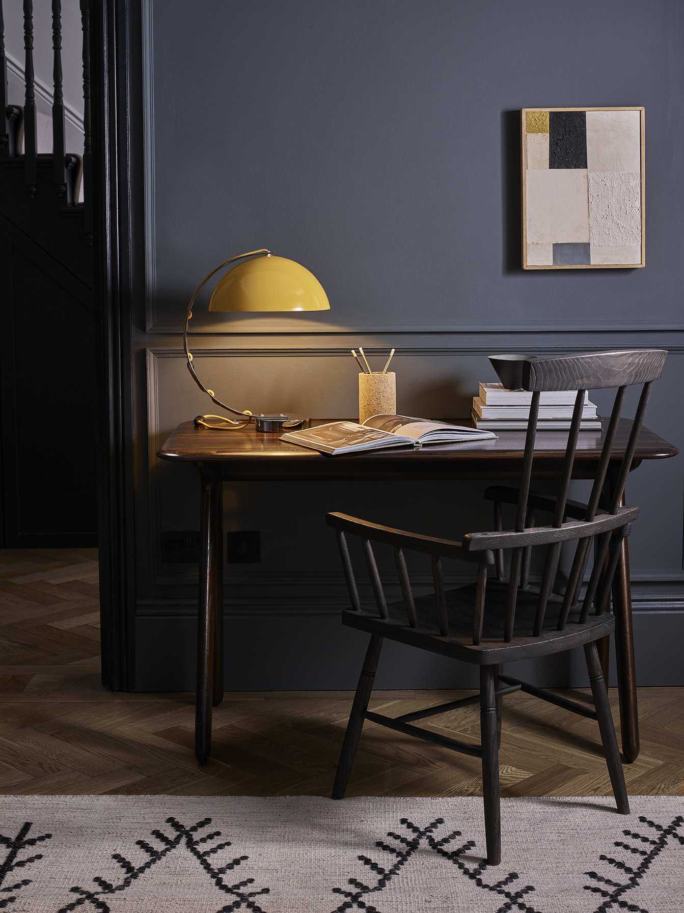 Matching dark wall paint and furniture and contrasting yellow lamp and hint of yellow in wall hanging