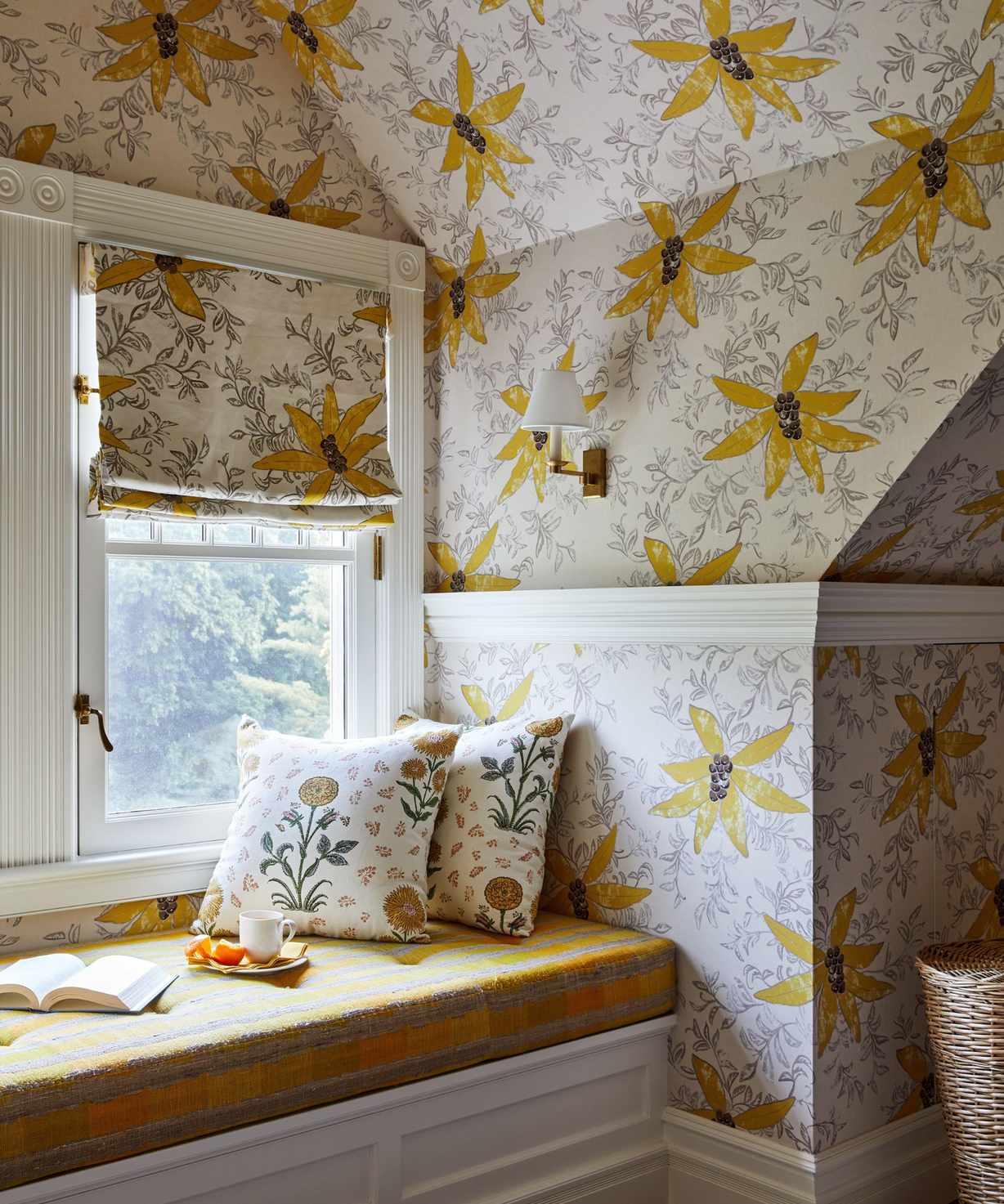 Window seat with yellow floral wallpaper, built-in bench with yellow plaid cushion, floral throw pillows, and a matching blind