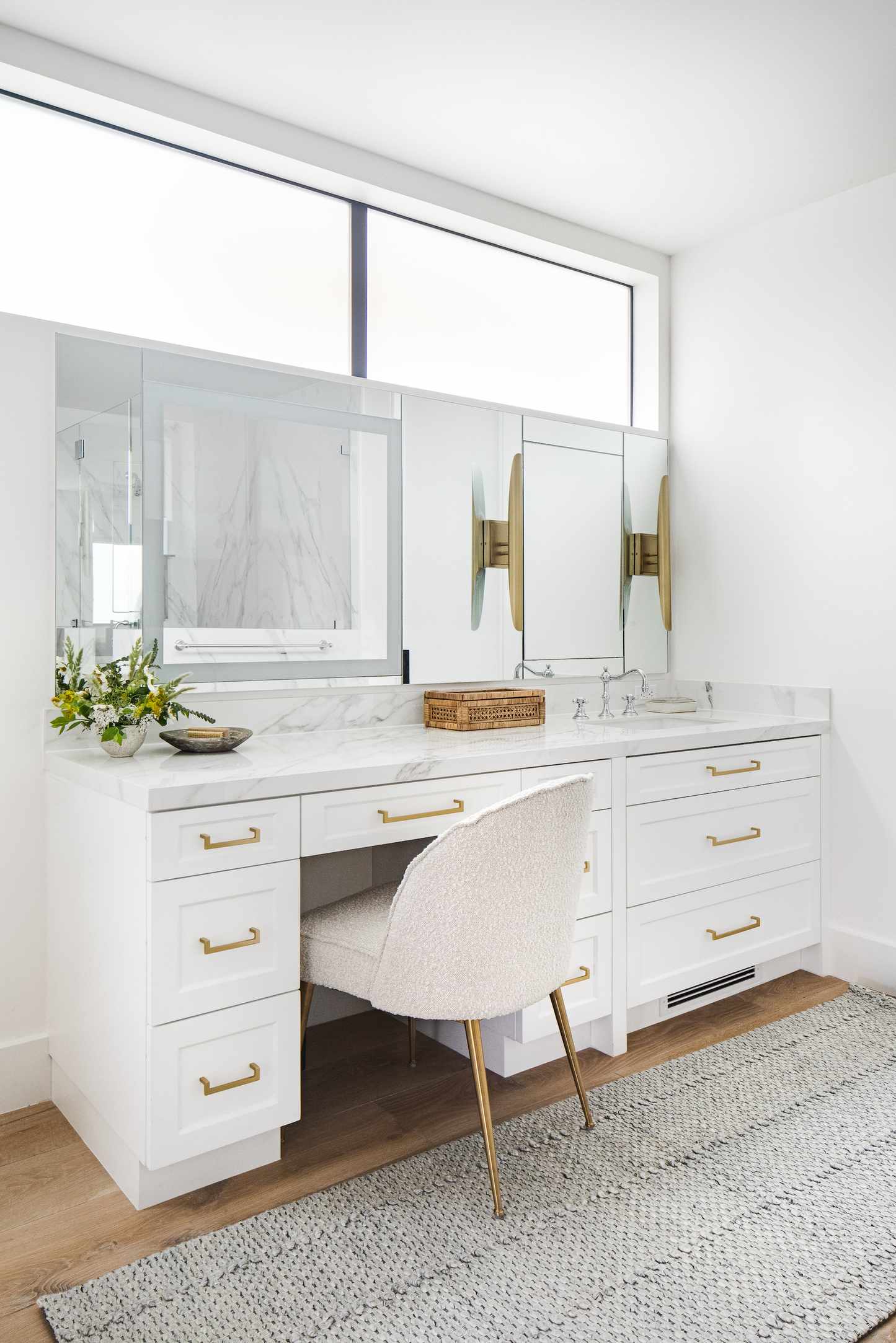 white bathroom with marble topped vanity and make up space. Mirrors, chair for make up vanity end