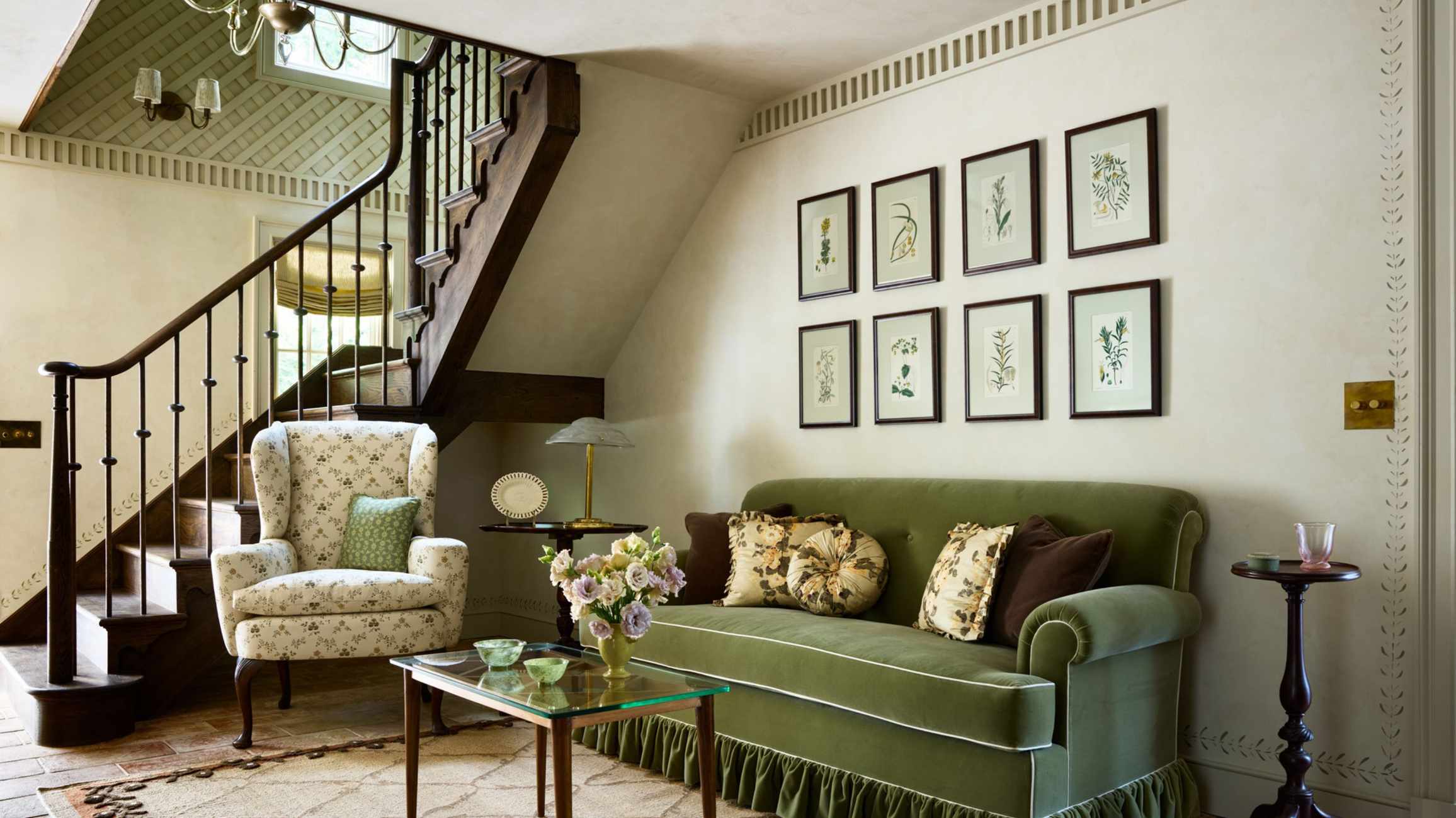 Tonal green living room with a skirted velvet sofa, floral armchair and botanical art