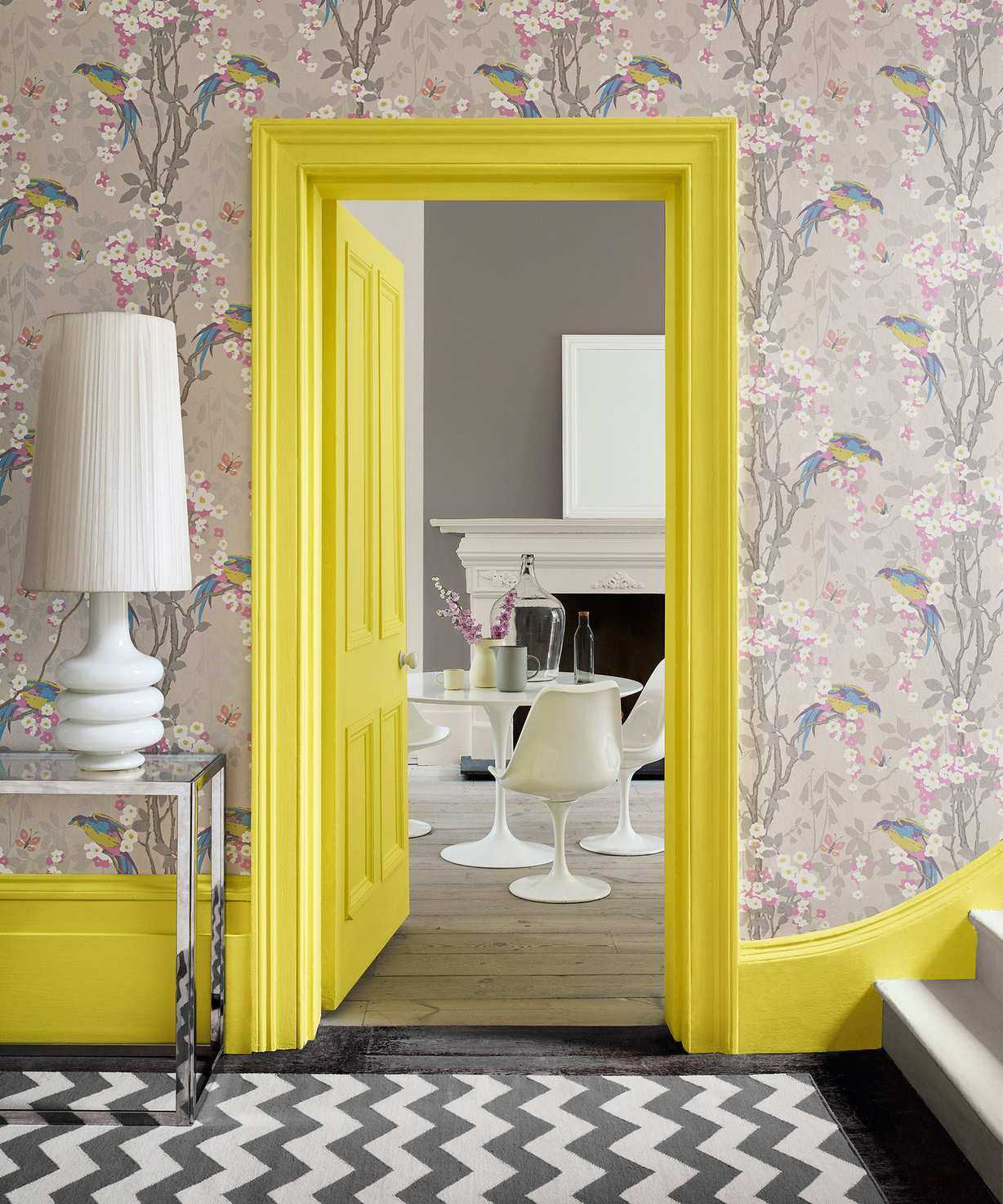 Bold hallway ideas, with brightly colored yellow woodwork and neutral patterned paper along with a monochrome zig zag rug.