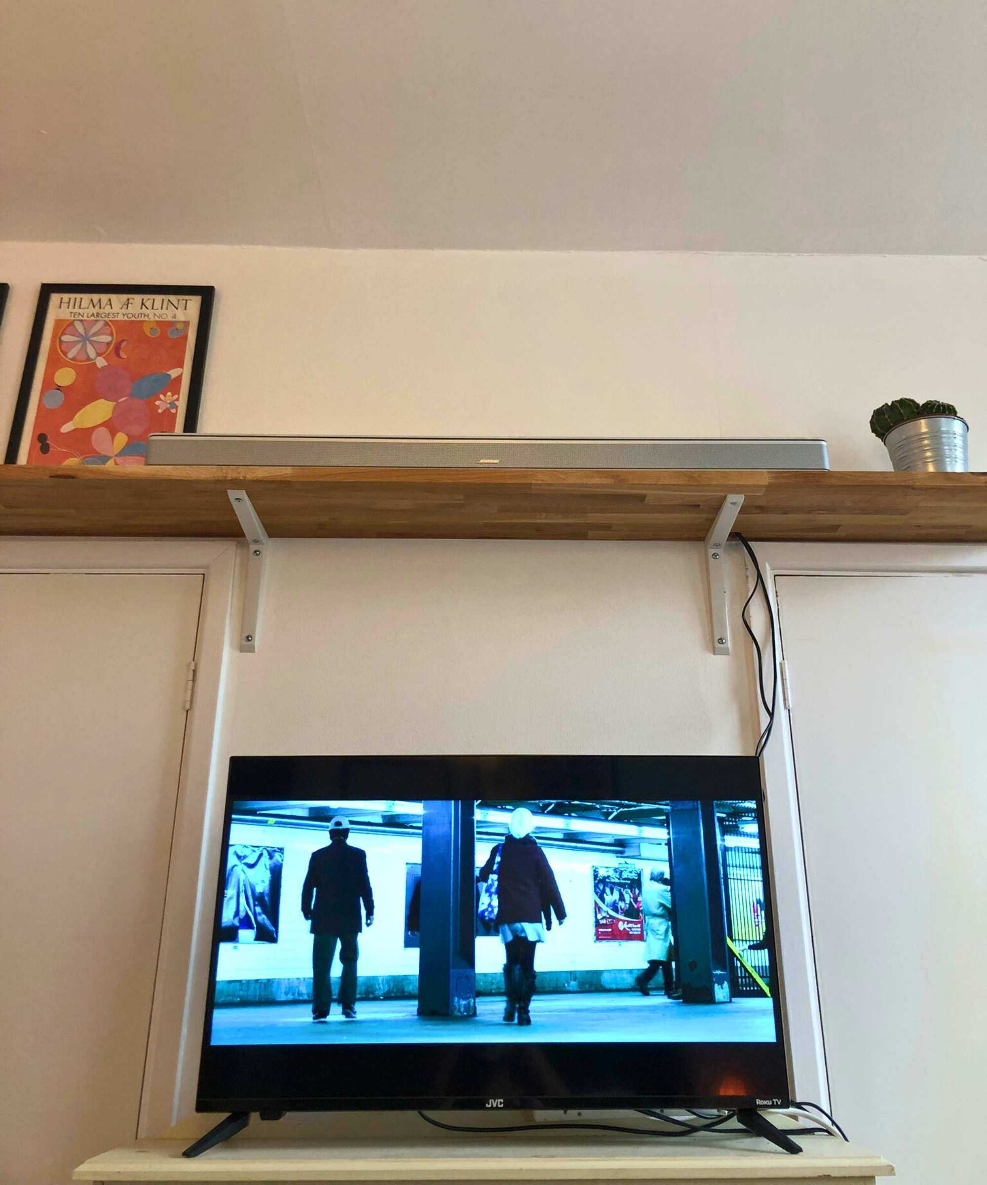 The Bose Smart Ultra Soundbar on wooden shelf above TV showing John Wick Chapter 2 in Dan Fauzi's home.