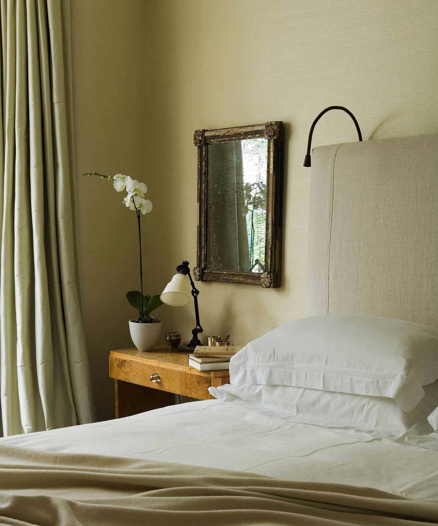 bedroom in neutral color scheme with potted orchid next to bed