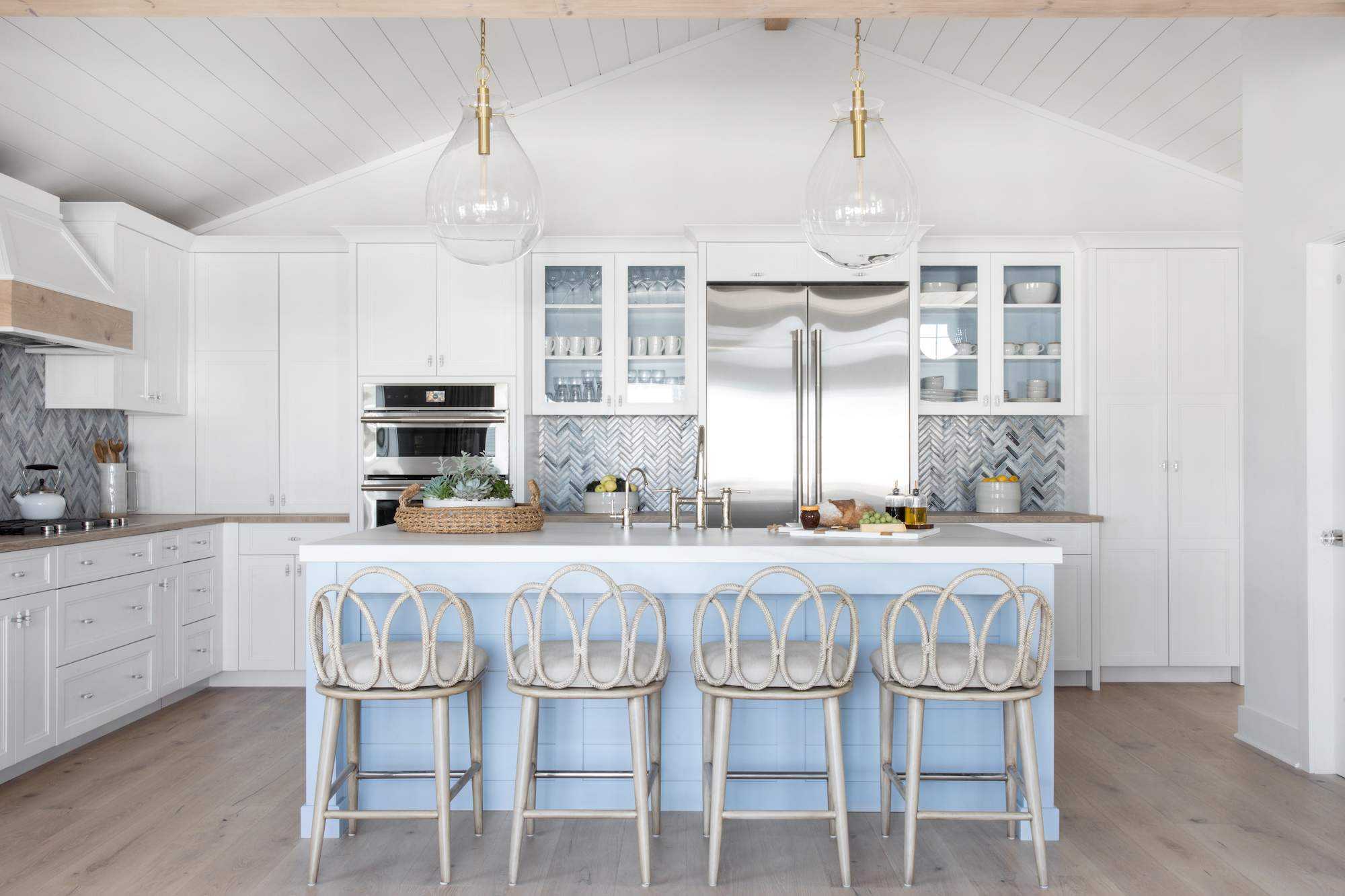 white and blue kitchen coastal style, with metallic tile backsplash, blue painted island, clear glass pendants, shiplap ceiling