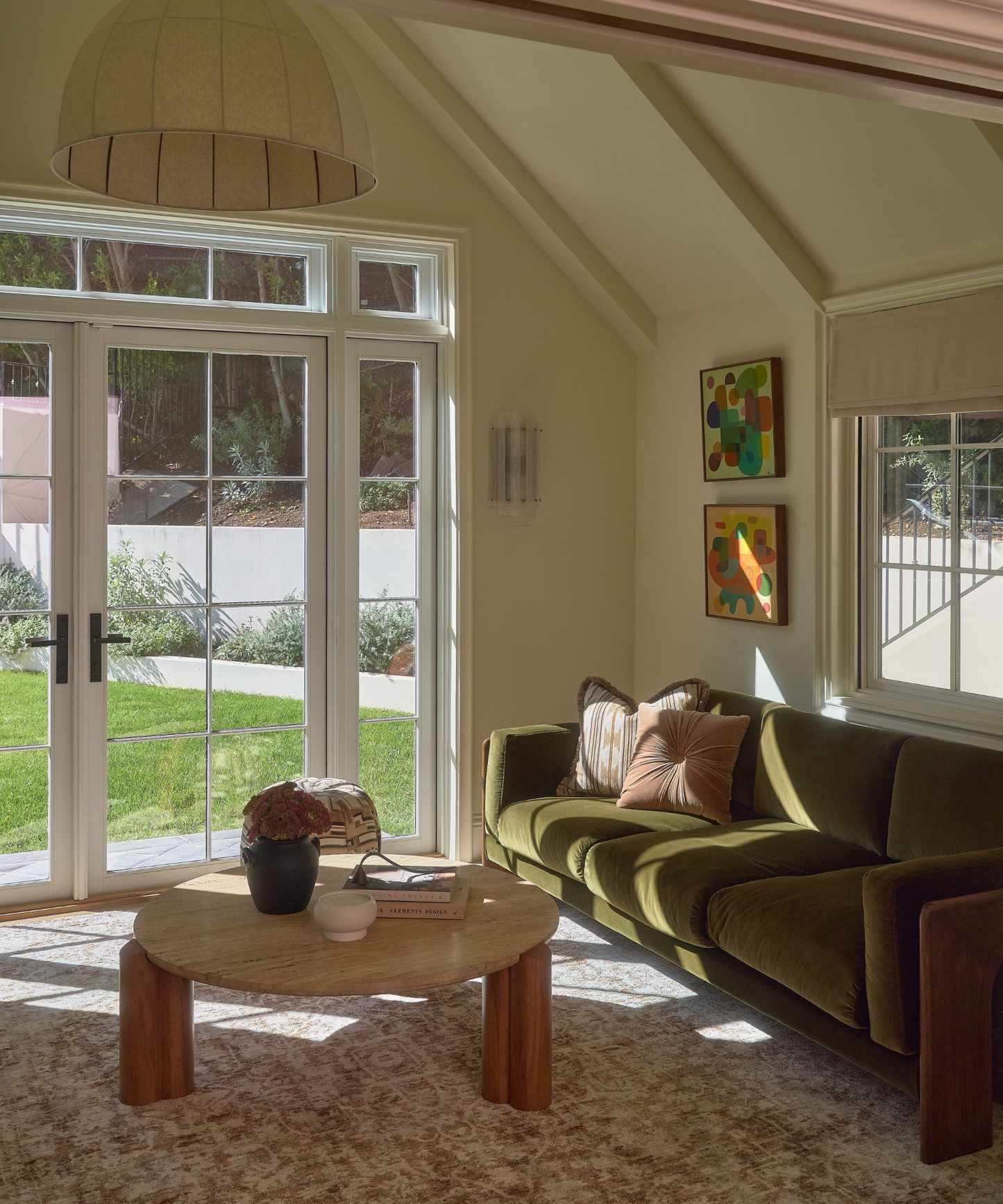 a primary bedroom suite with a lounge area with french doors, vintage style rug, green couch and coffee table