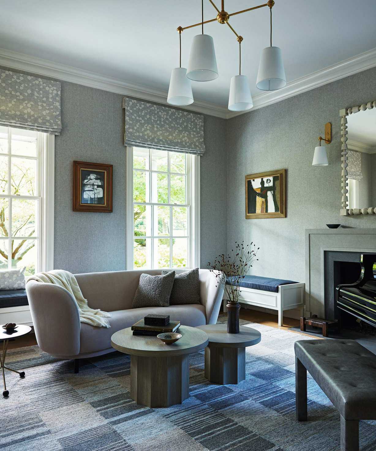a soft blue music room with patchwork rug, fireplace, curved couch and round coffee tables