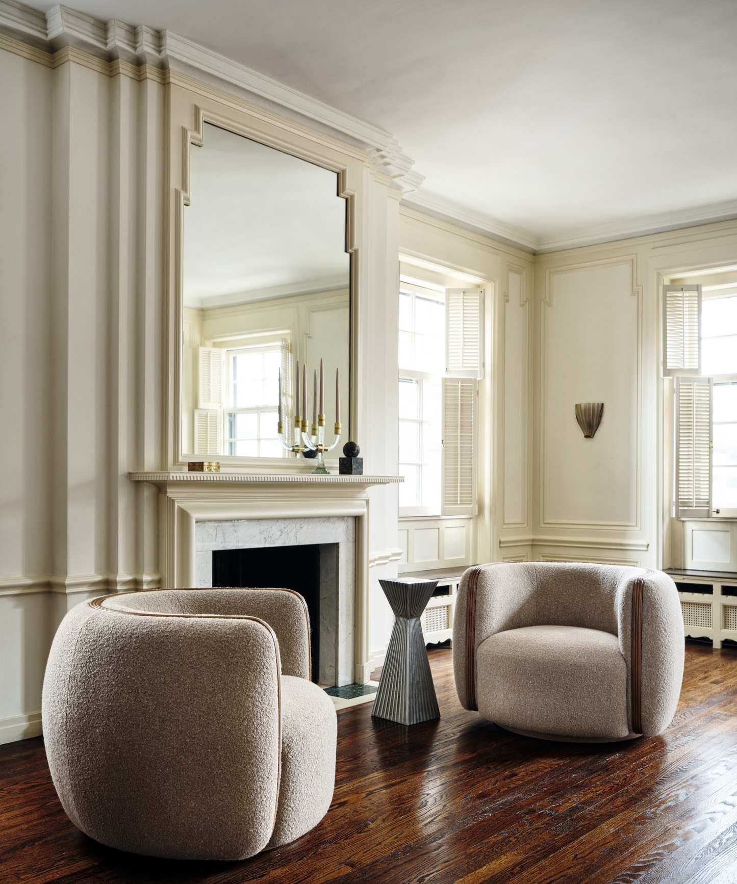 a sitting room with two chairs, a geometrically shaped drink table, and a fireplace