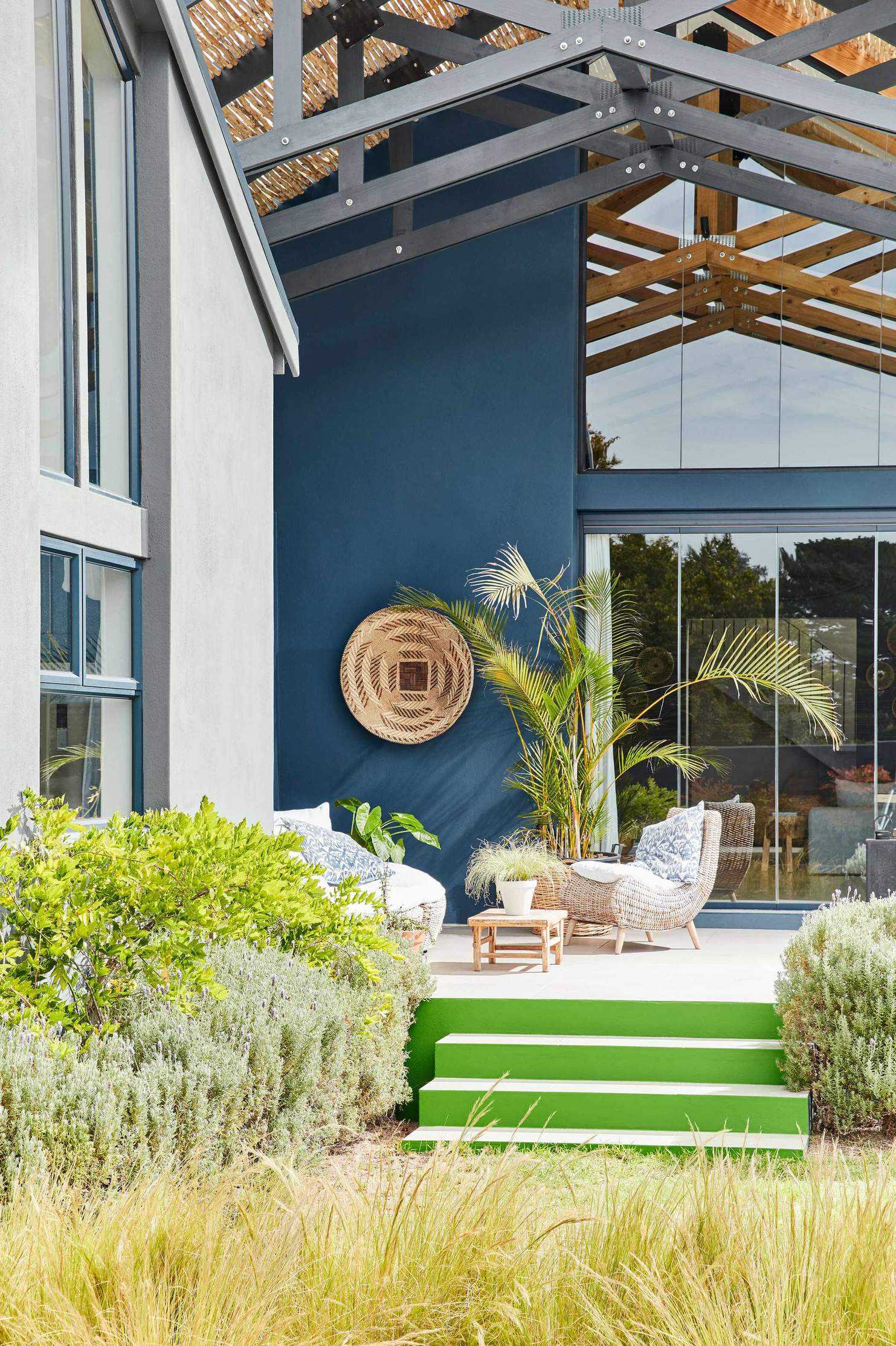 A large house with a blue outdoor wall and bright green steps leading down to a grassy garden