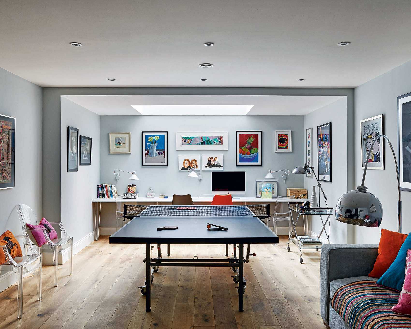 A large neutral kids playroom with table tennis table and colorful cushions and wall art.