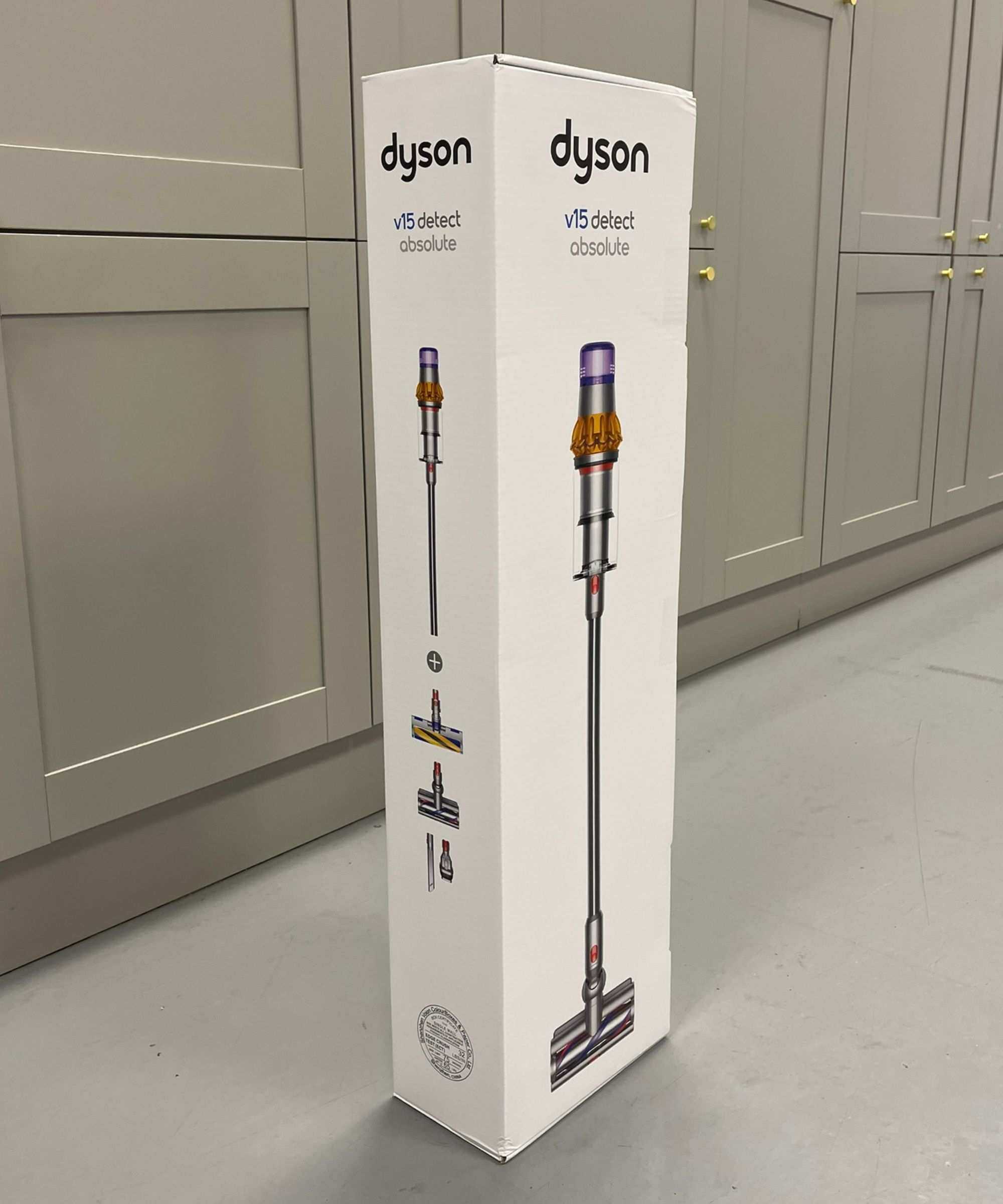 White cardboard Dyson V15 Detect box with the cordless vacuum and its attachments printed on the outside, in front of gray cabinets in Future test center