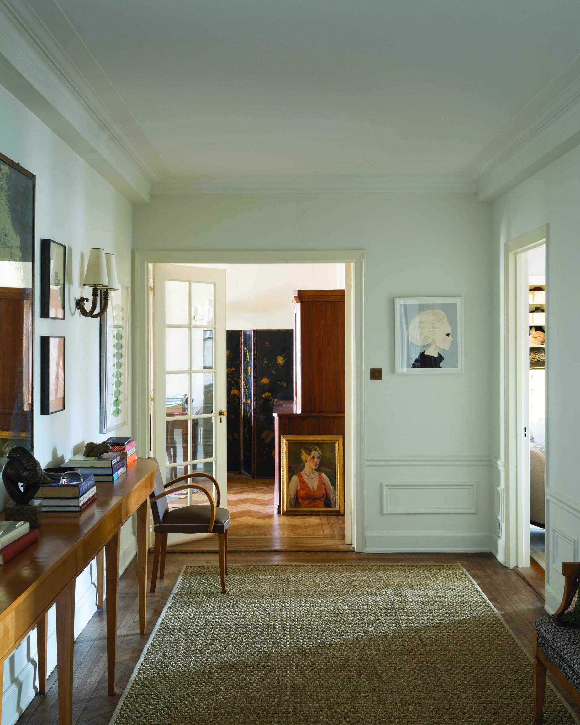 White painted hallway idea with jute rug, artwork and mid century wooden console table.
