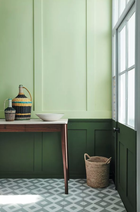 Hallway with paneling in light and dark green and patterned tile floor