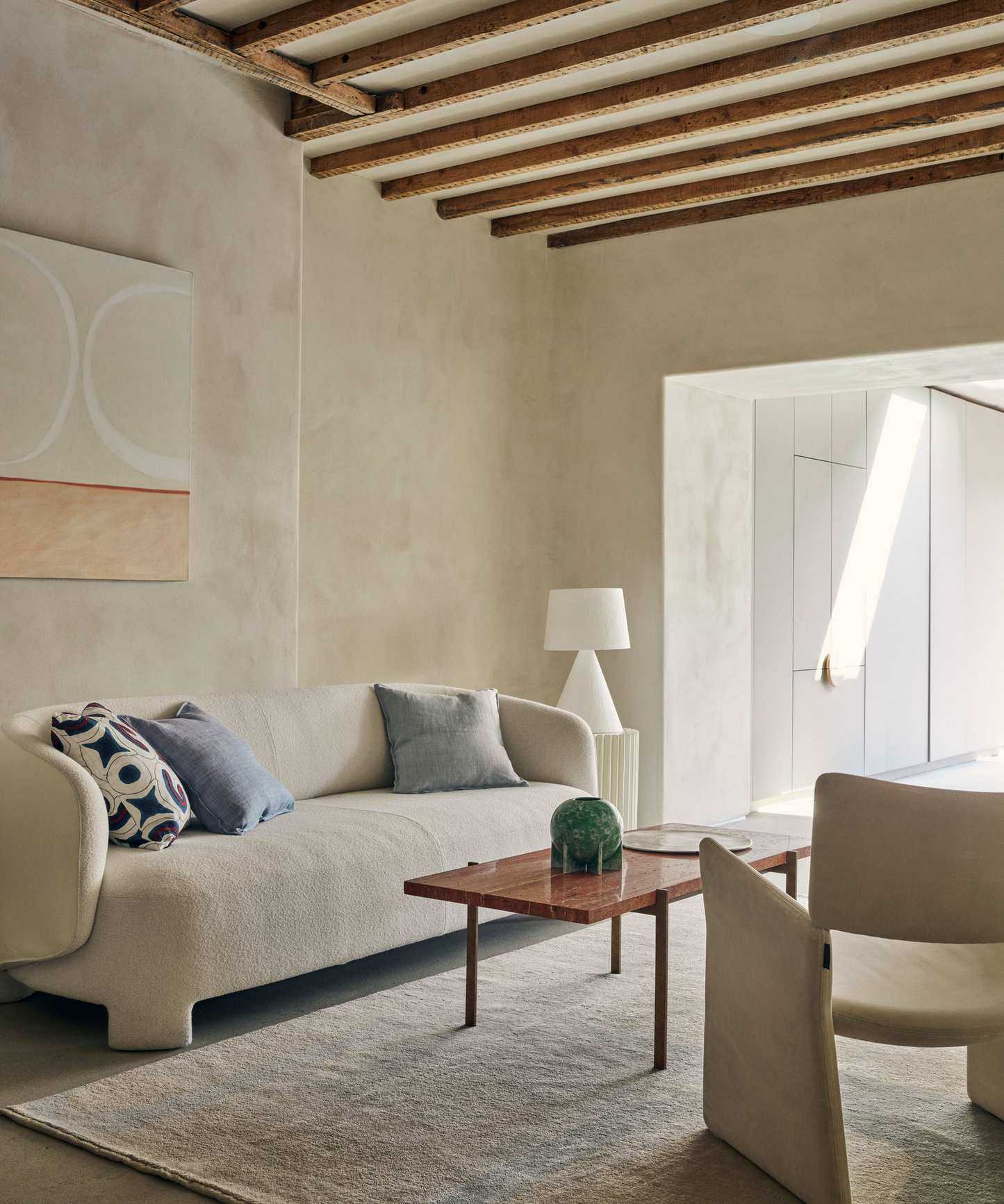 living room with curved white sofa, abstract art work and red marble top coffee table