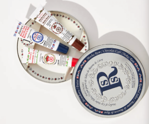 A tin with a big "R" on it is pictured, with the lid off. Inside are three tubes of lip balm.