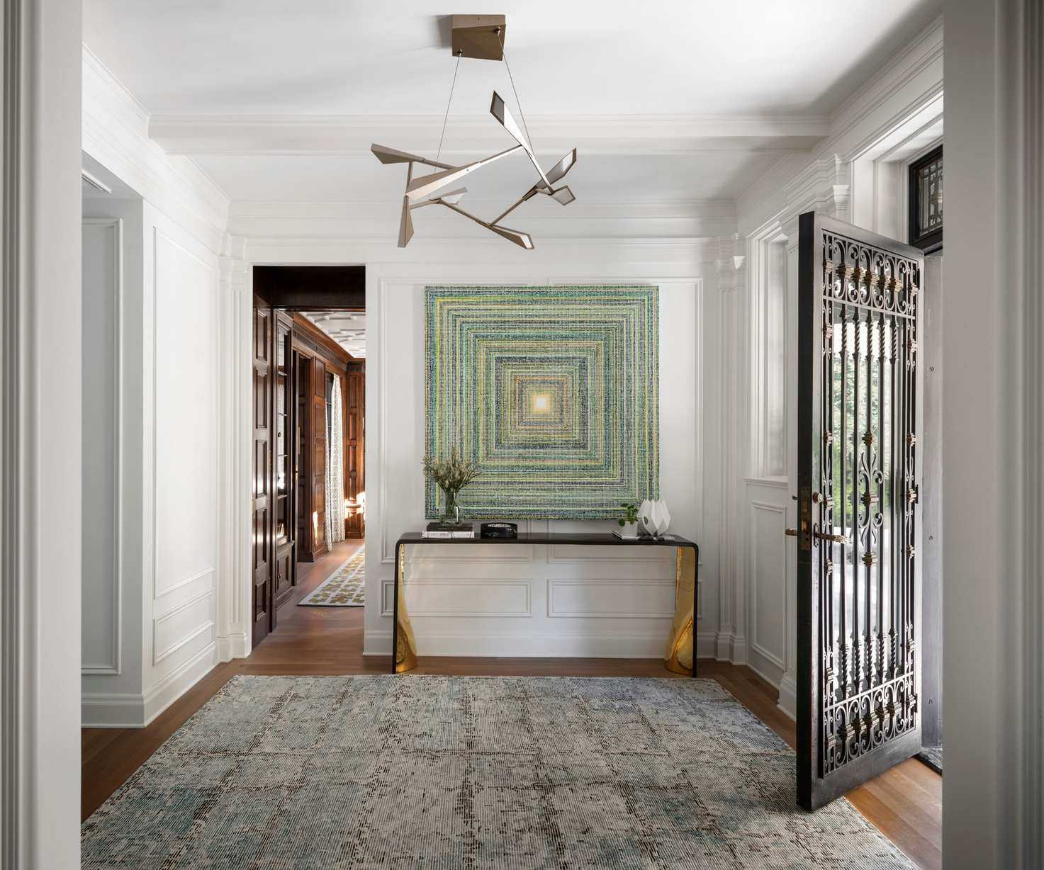 entrance foyer with wooden floor and door open and console with artwork above
