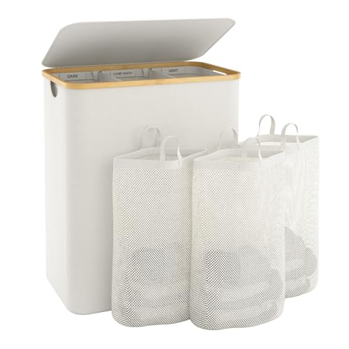 A cream laundry basket with a bamboo trim and flip lid, with three removable mesh bags in front of it.