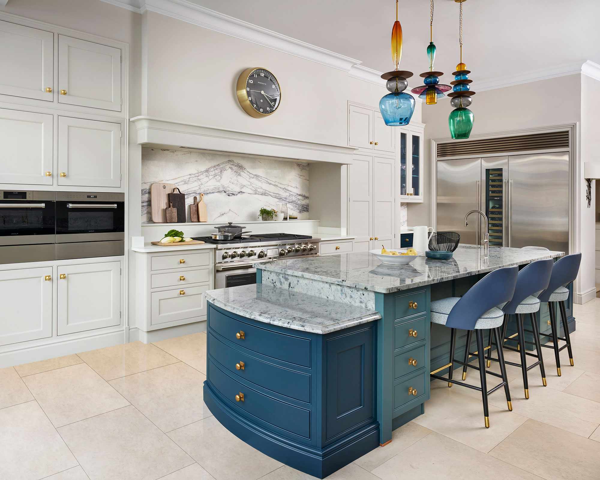 Marble island with blue cabinetry and chairs, in a large neutral scheme