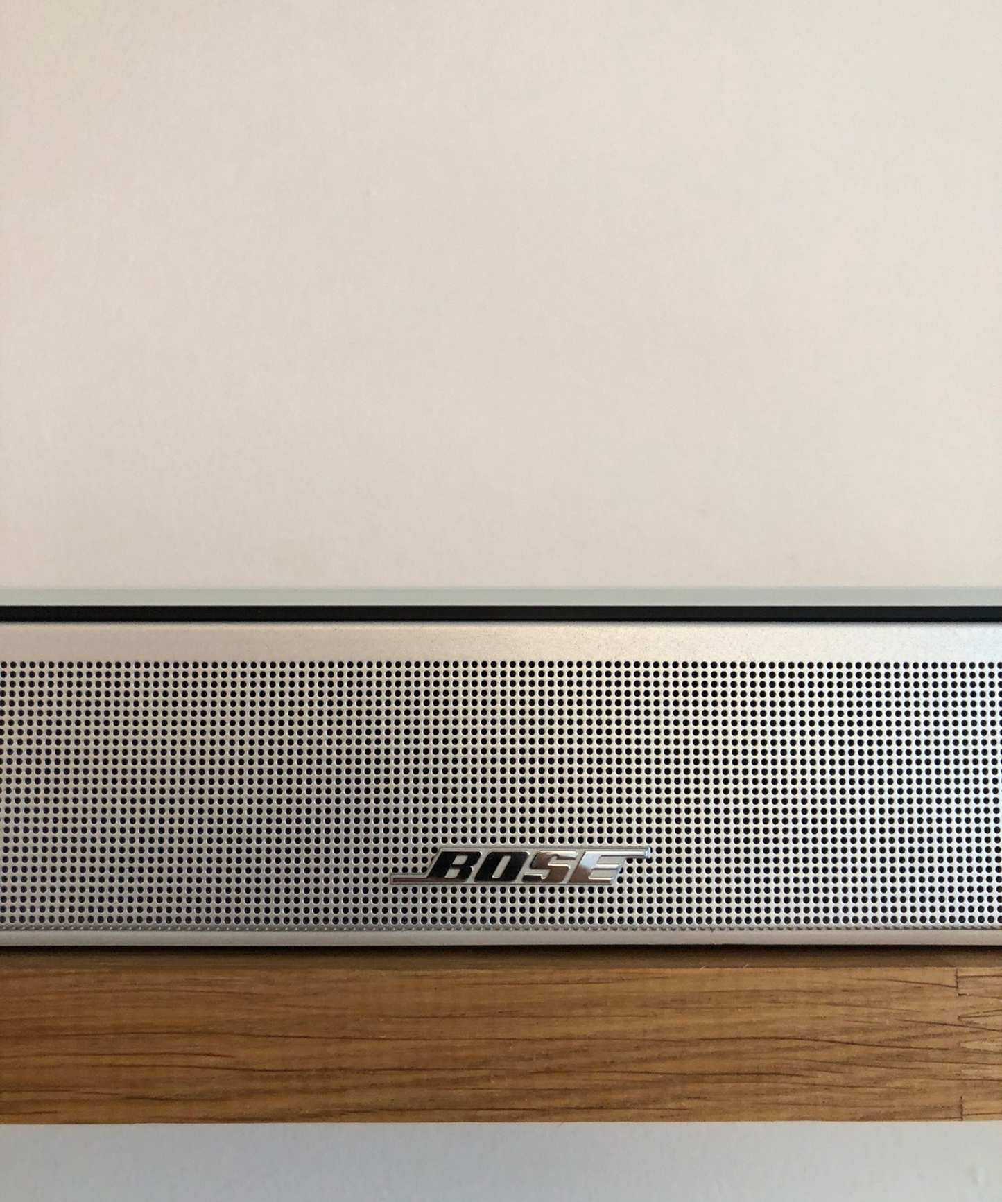 Closeup of the Bose Smart Ultra Soundbar on wooden shelf in front of white wall in Dan Fauzi's home.