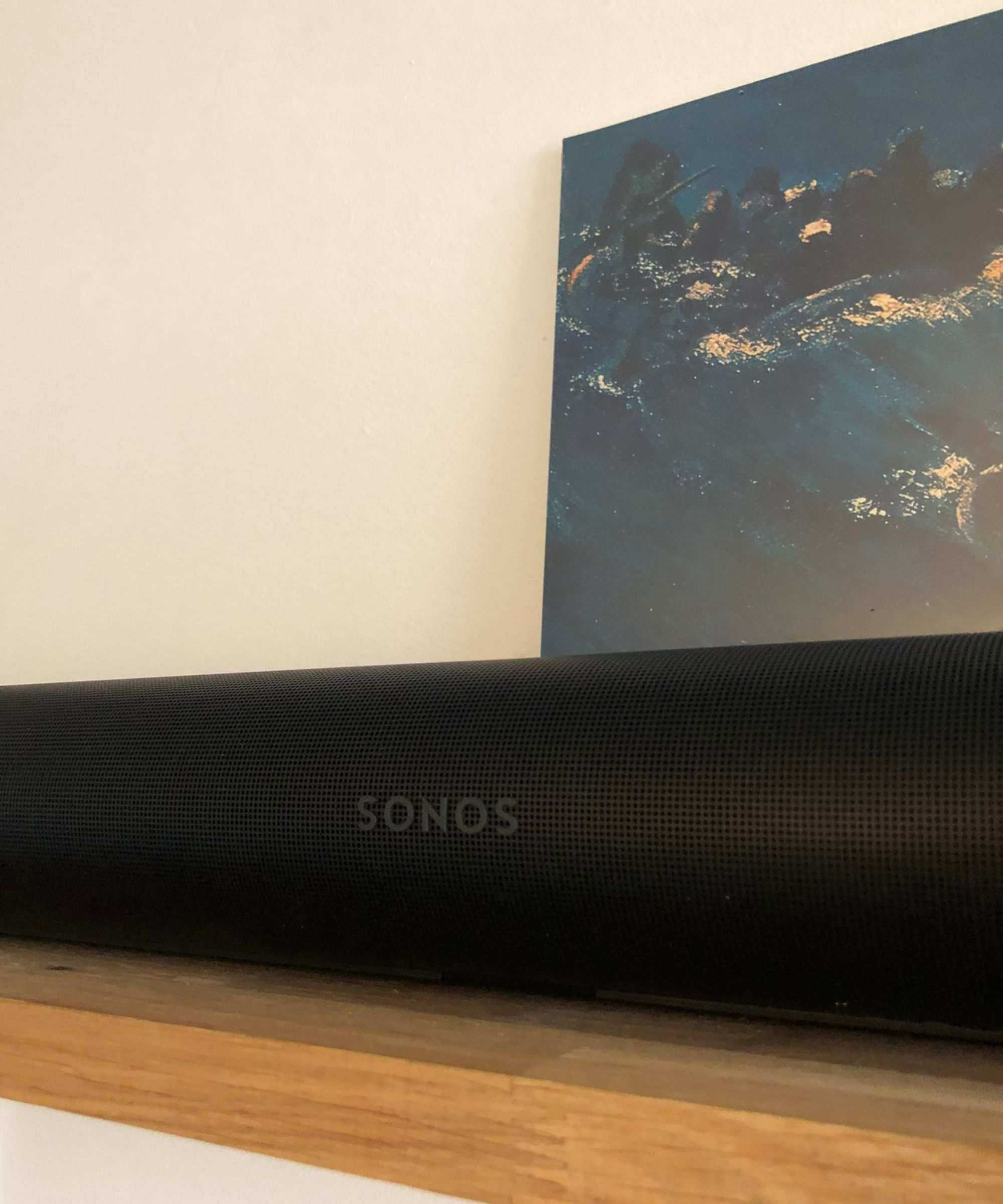 Sonos Arc Ultra soundbar on wooden shelf in front of vinyl sleeve of The Avalanches' Since I Left You and white wall.
