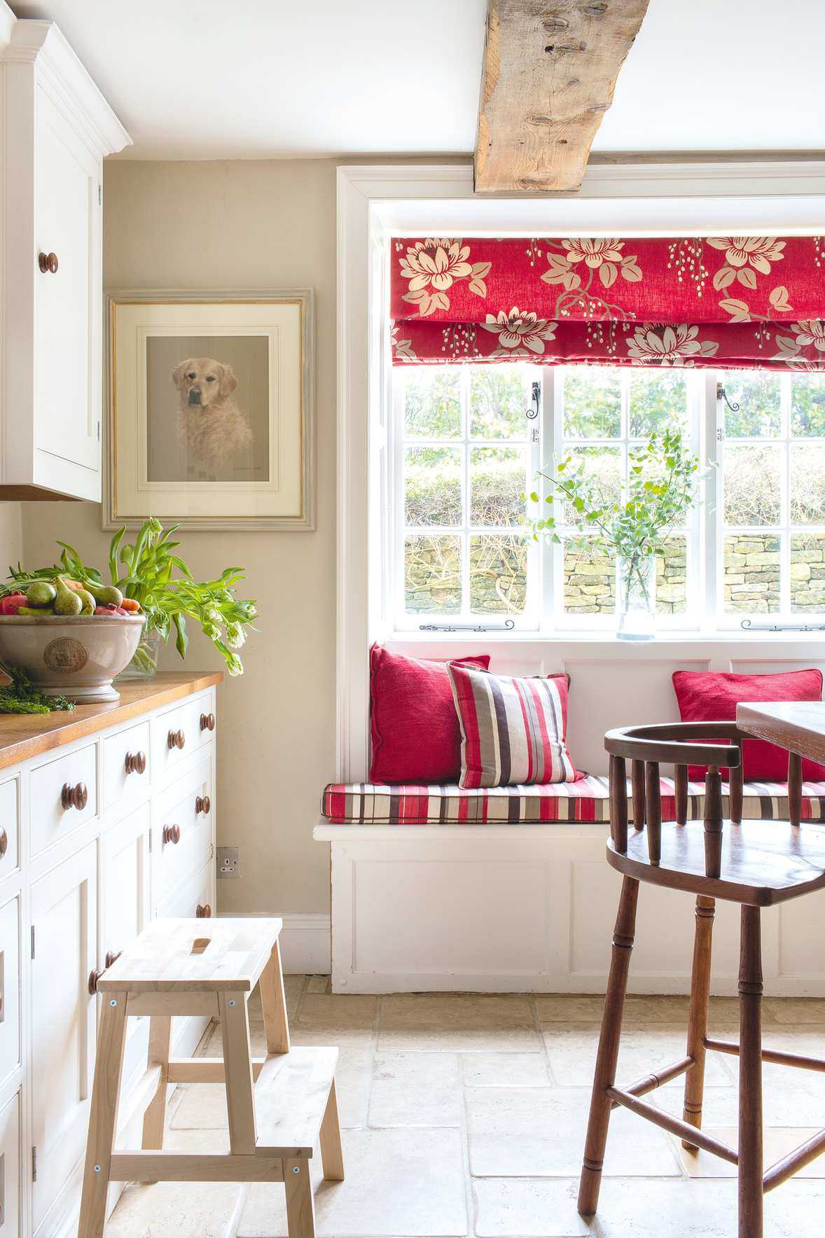 white kitchen with wooden worktops and cabinetry plus window seat with red blinds
