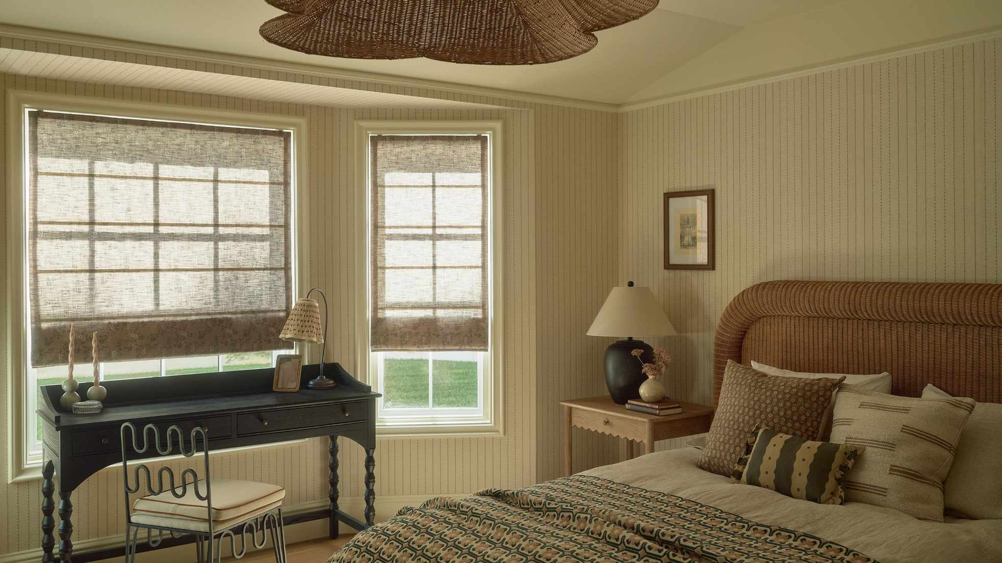 a soft paneled bedroom with a chunky rattan bed and a black twisted leg desk with wavy chair