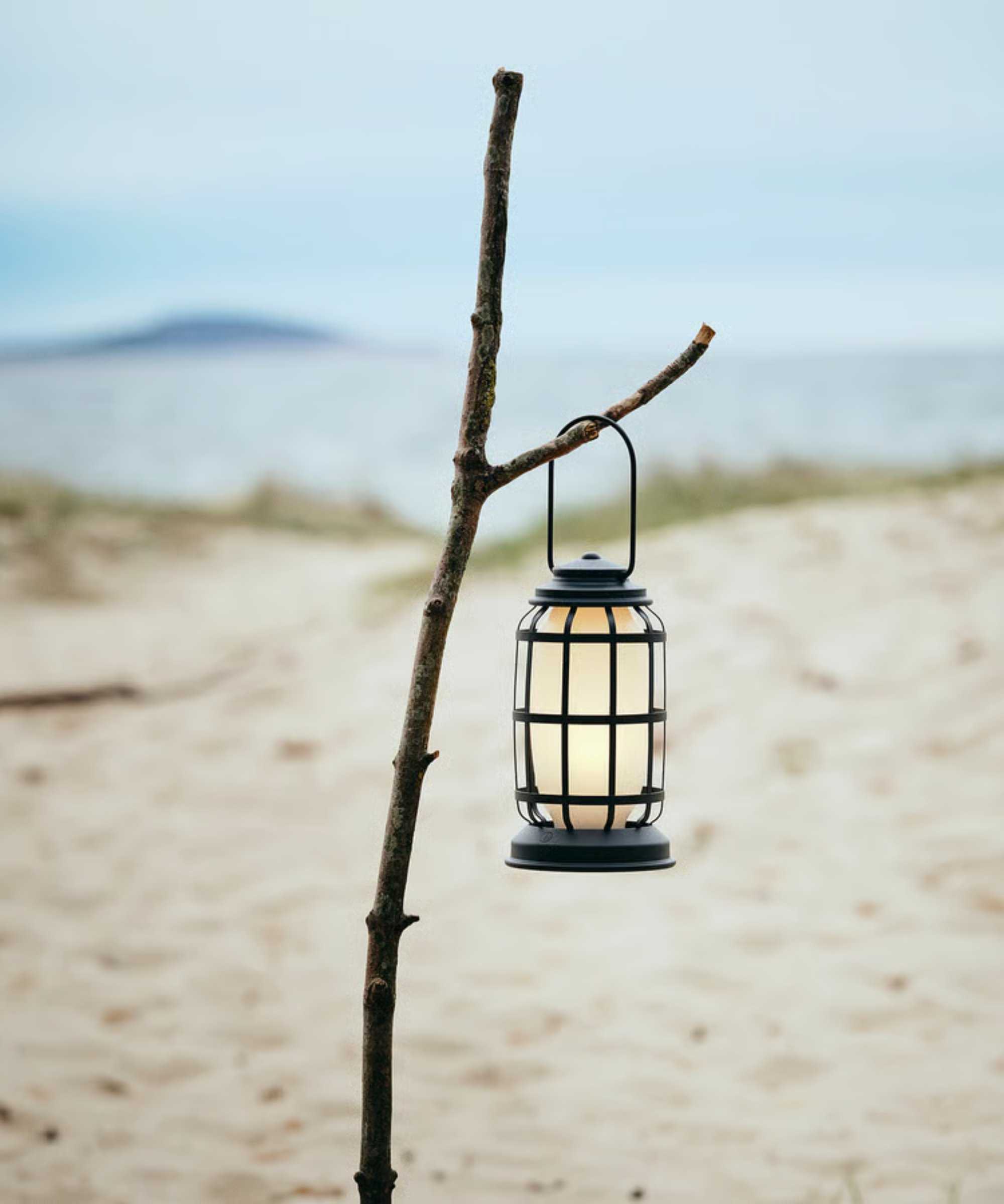 a lantern hanging from a stick on a beach