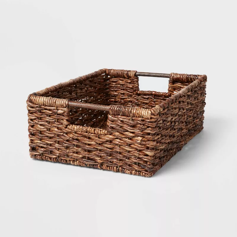 A dark down woven lacquered storage basket with cut-out handles