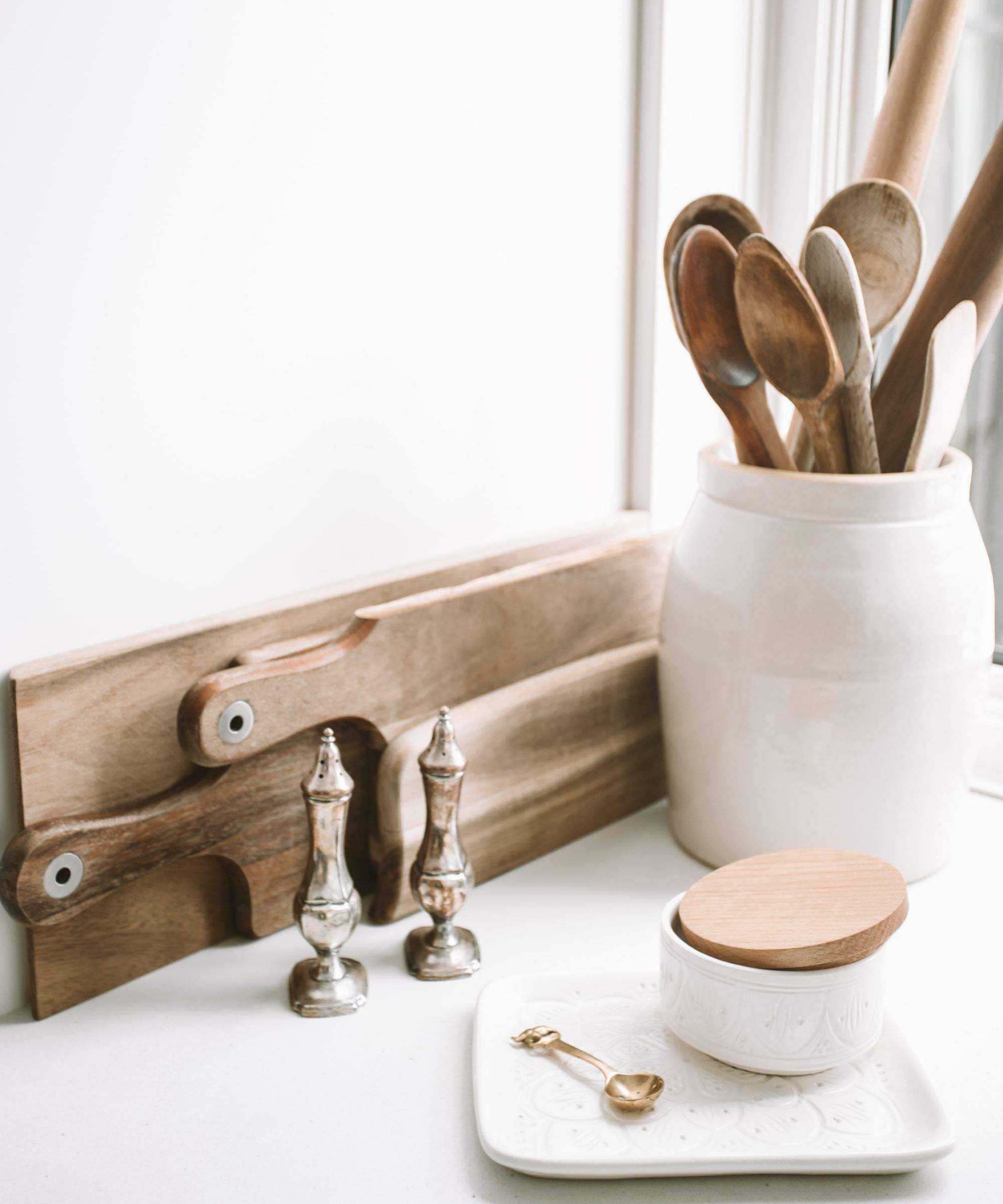 Kitchen chopping boards against a wall with a pot of wooden kitchen utensils