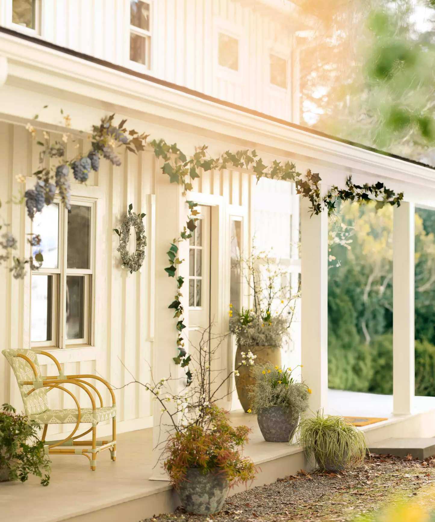a front porch with decorative garland hanging from the porch and an assortment of potted plants around the porch